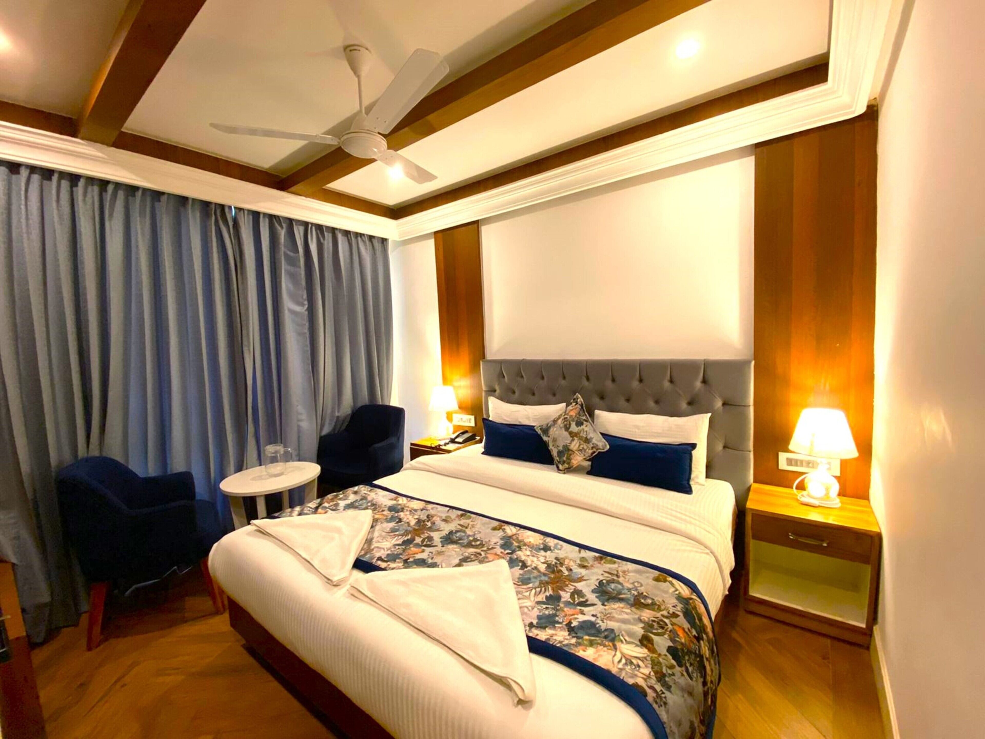 A hotel room with a large bed, a ceiling fan, a desk, and a chair.