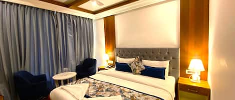 A hotel room with a large bed, a ceiling fan, a desk, and a chair.