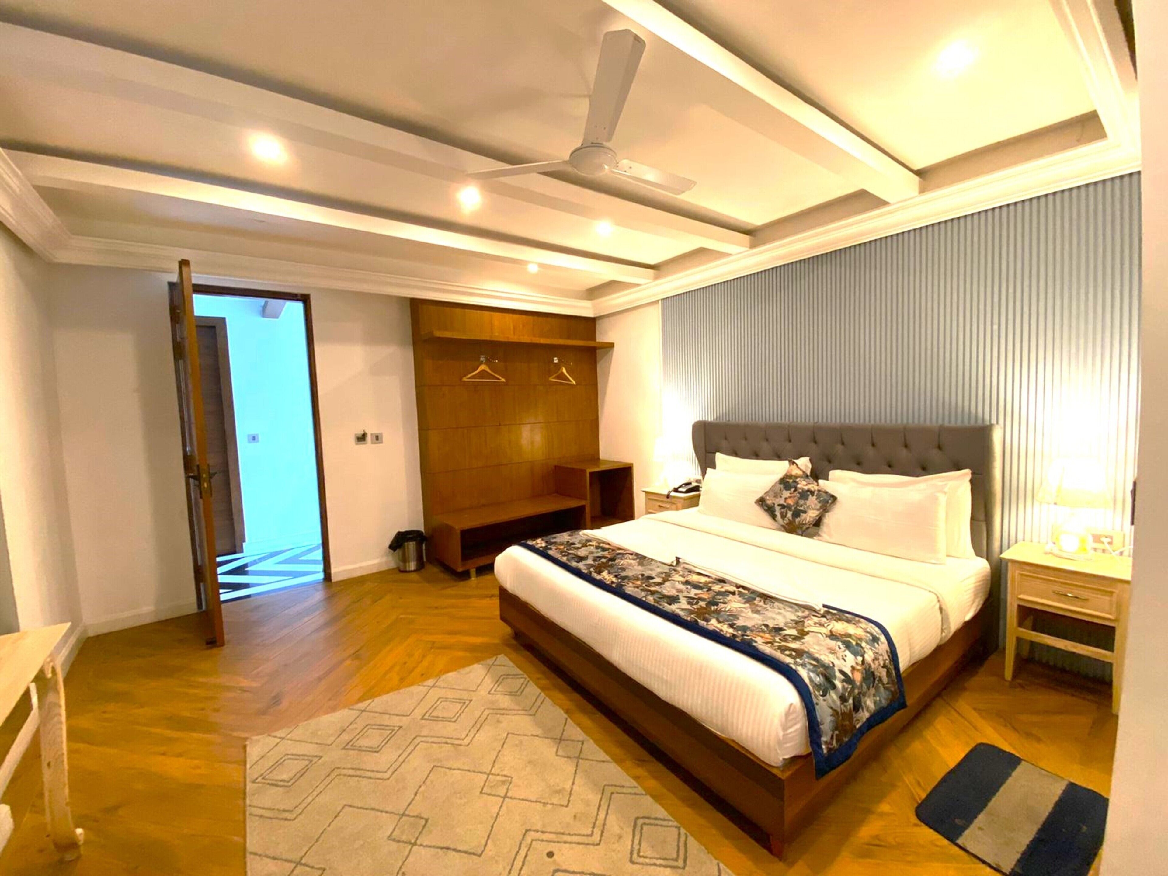 Une chambre moderne avec un grand lit, un ventilateur de plafond et un dressing.