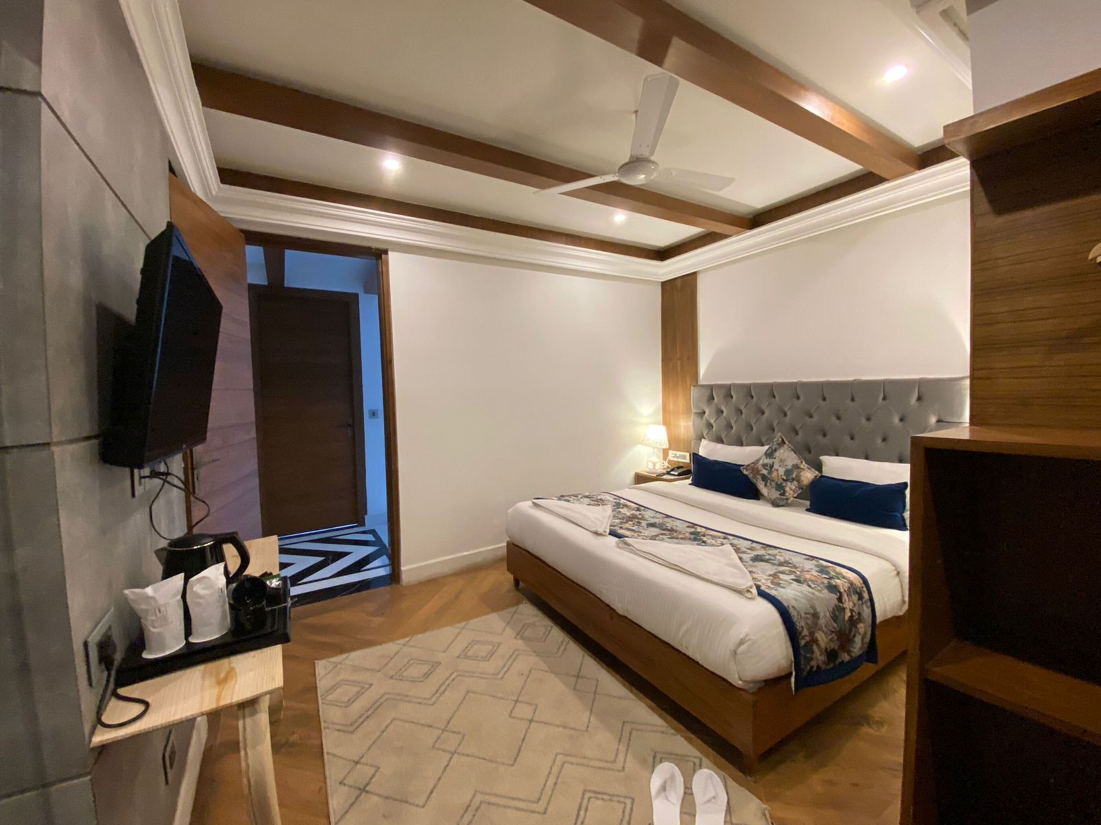 Een moderne hotelkamer met een groot bed, een flatscreen televisie aan de muur, een plafondventilator en een houten hoofdbord.