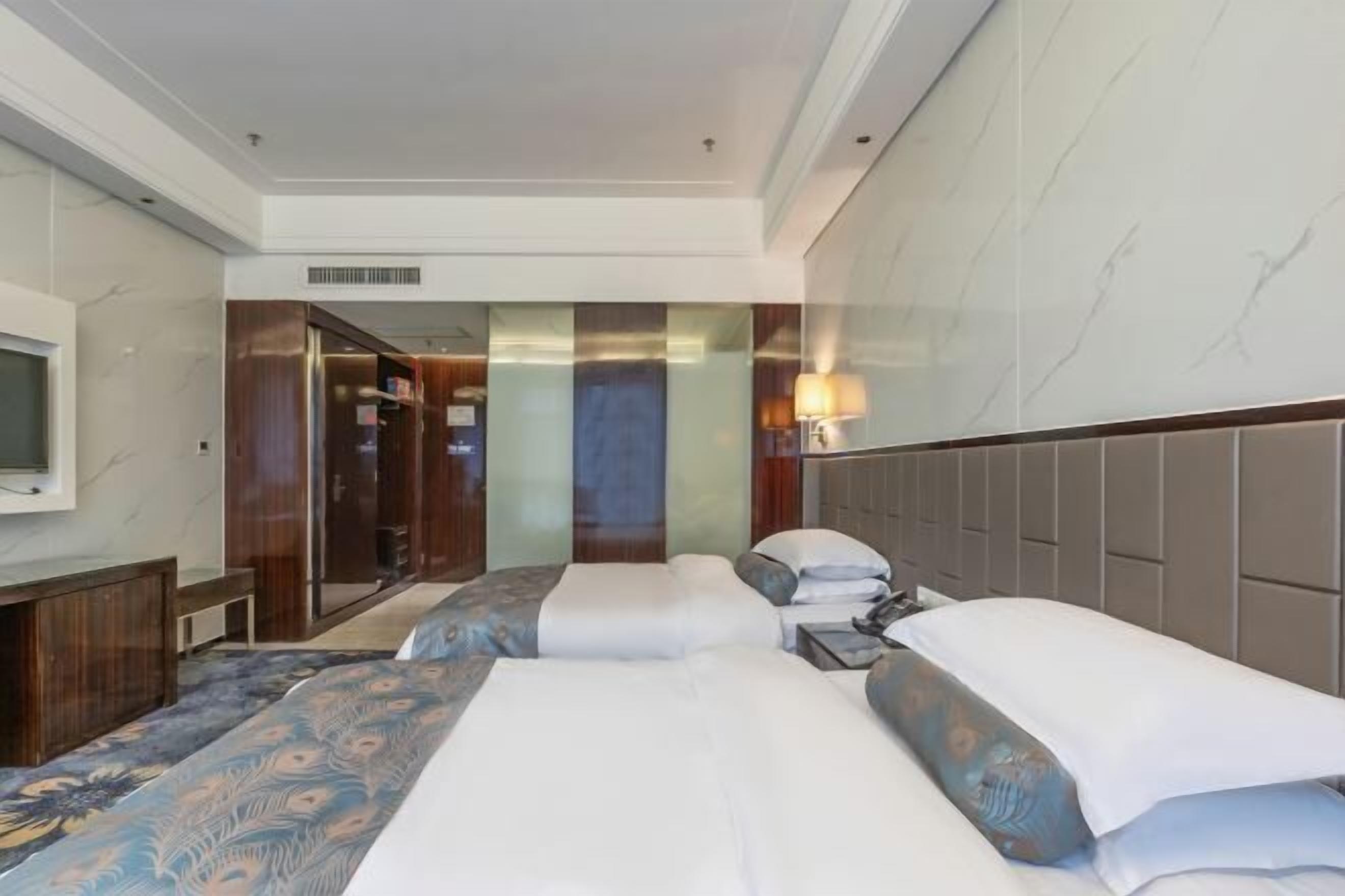 Una habitación de hotel con dos camas, televisión, escritorio y baño con espejo.