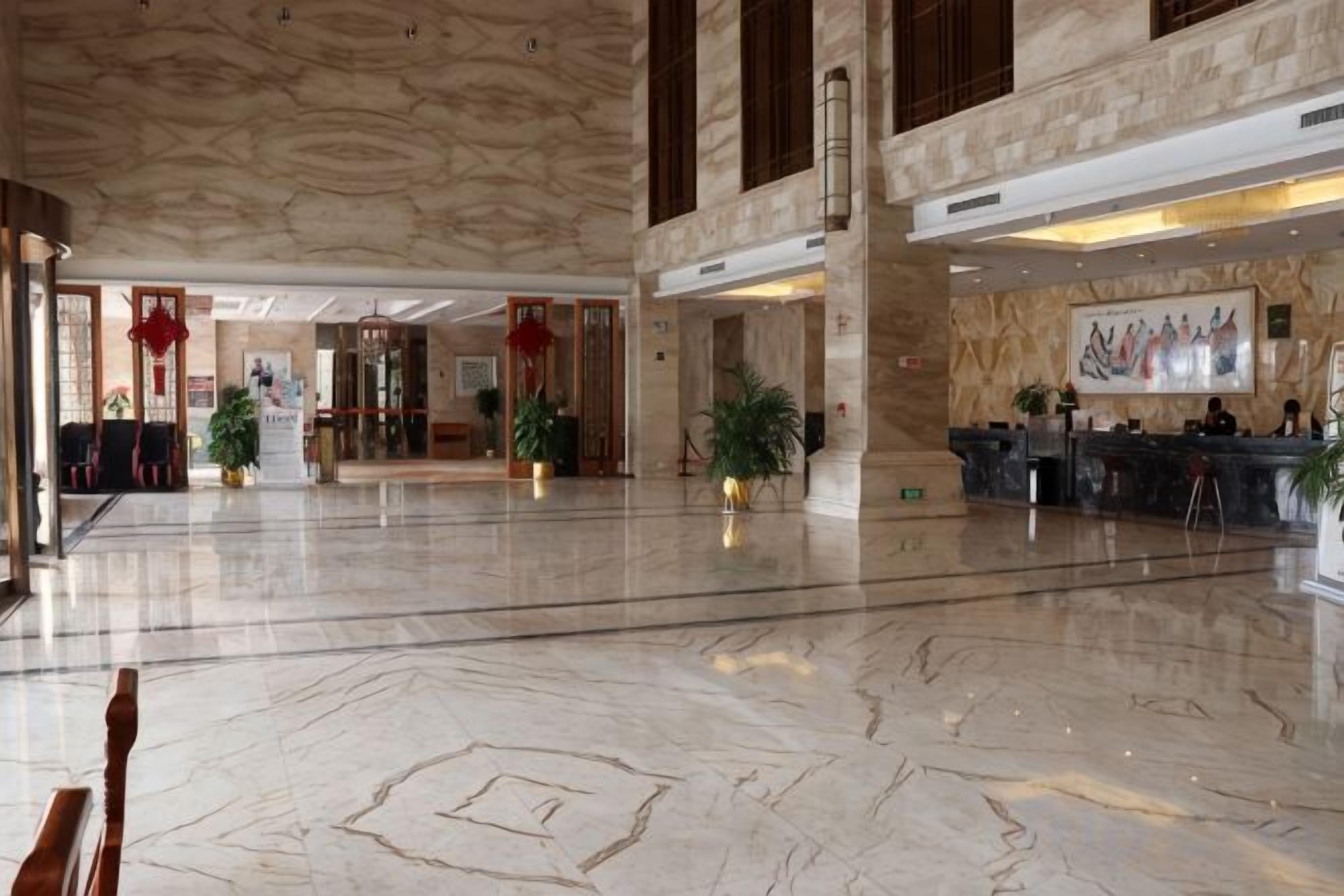 A spacious lobby with marble flooring, a reception desk, and a large painting on the wall.