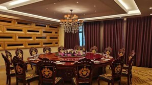 A round dining table with ornate chairs, a chandelier, and a floral centerpiece.