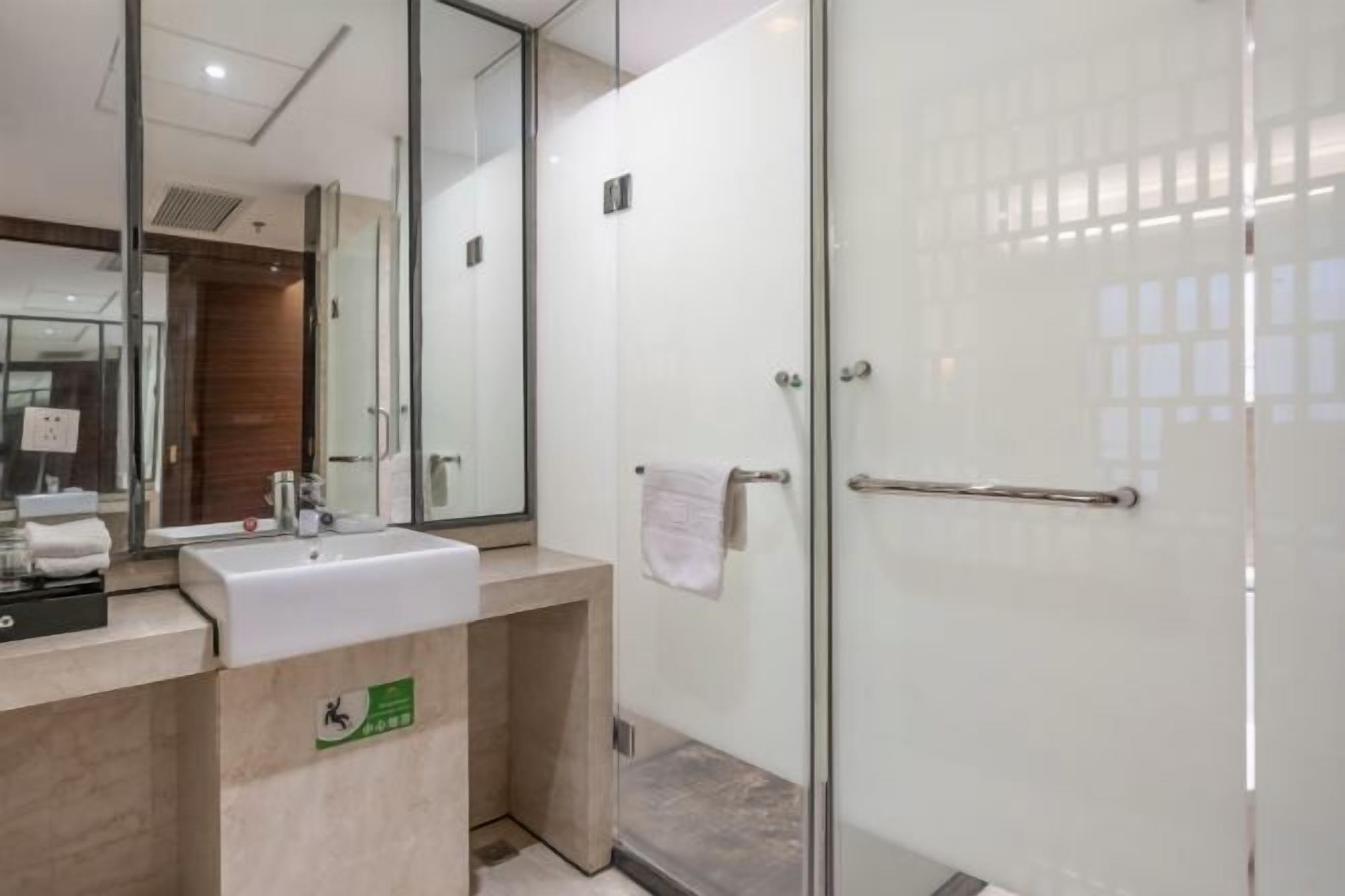 A modern bathroom with a glass shower enclosure, a sink with a mirror, and a towel rack.