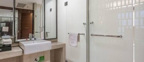 A modern bathroom with a glass shower enclosure, a sink with a mirror, and a towel rack.