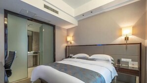 A hotel room with a large bed, bedside tables, a desk, and a chair.