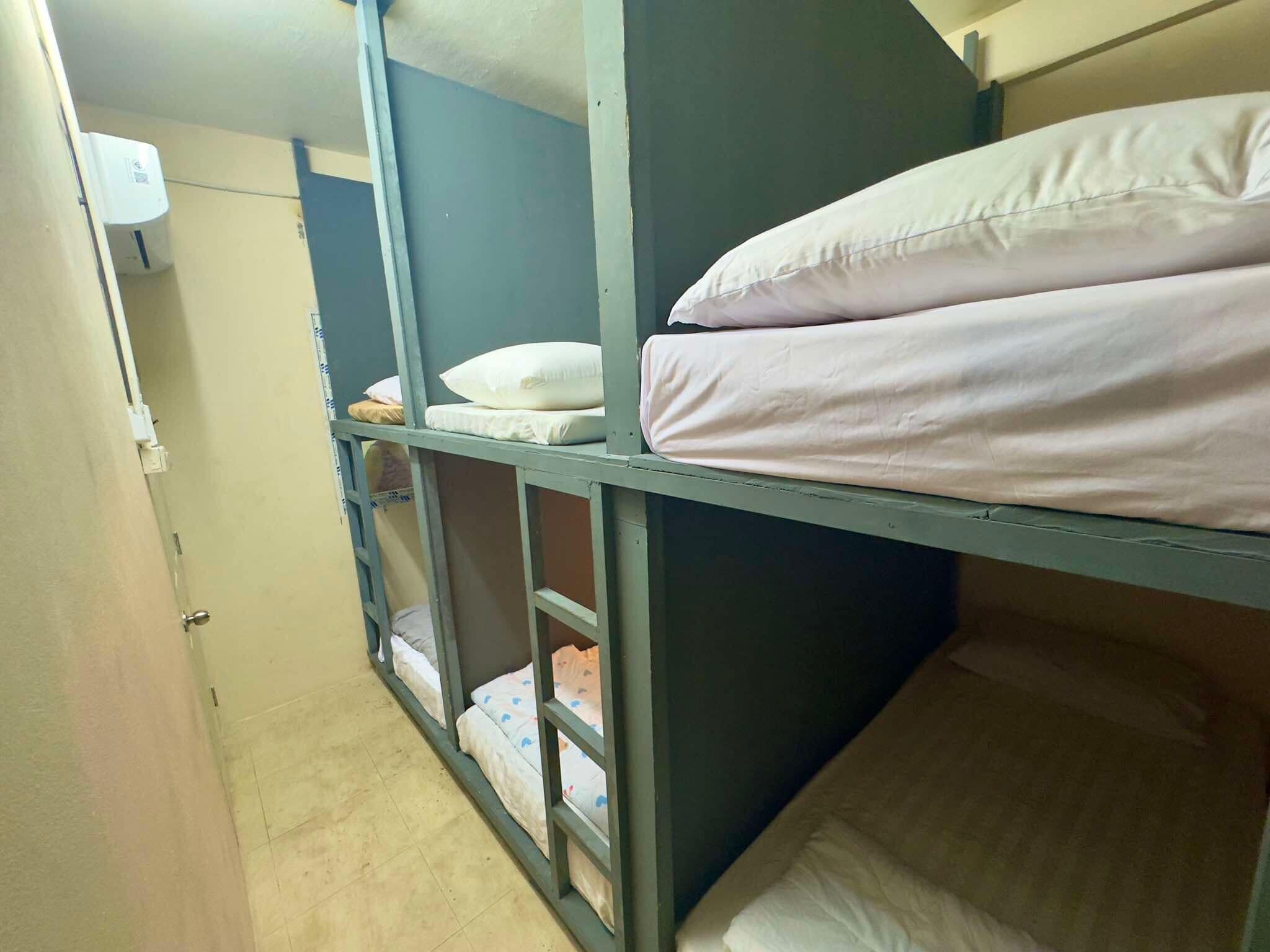 A bunk bed room with a door, a wall-mounted air conditioner, and a window.