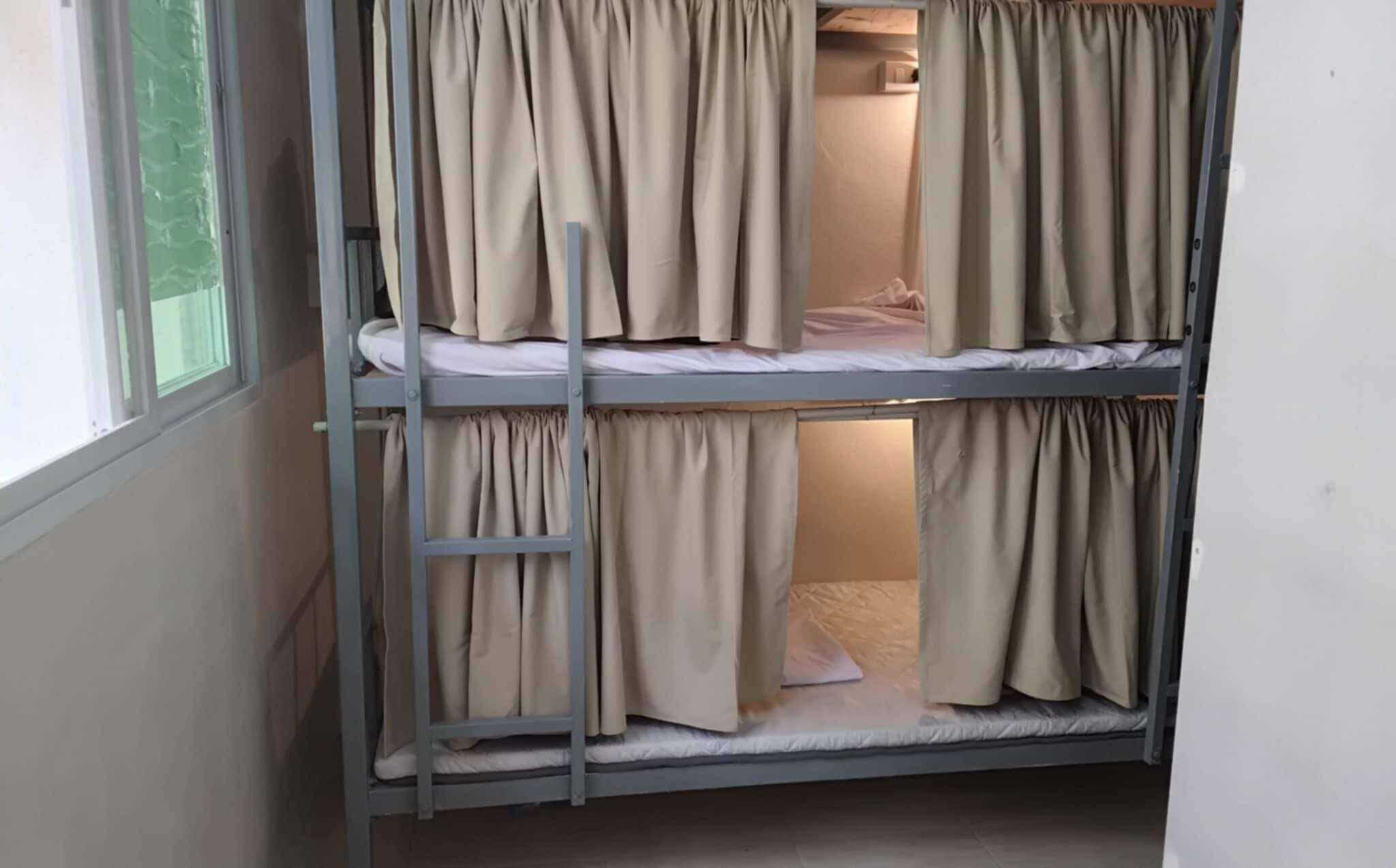 A bunk bed with curtains, a ladder, and a window.