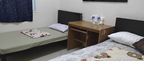 Une petite pièce simple, avec deux lits, une petite table et un tableau accroché au mur.