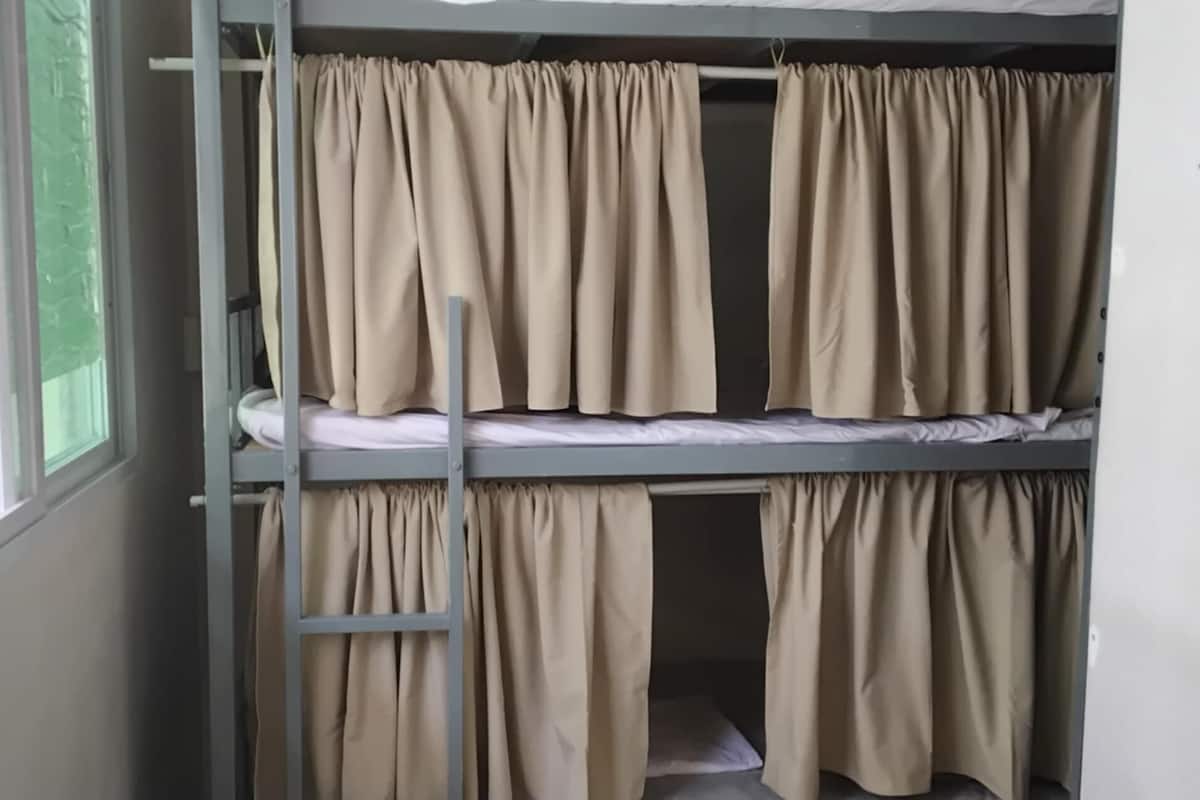 Una cama litera con cortinas color crema y una escalera.