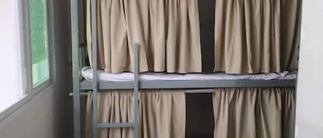 A bunk bed with beige curtains and a ladder.