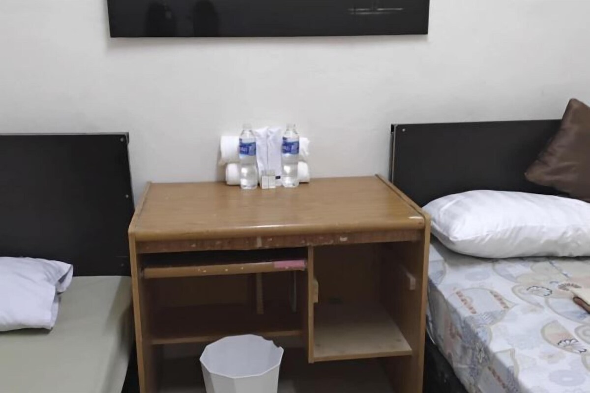 A small room with a bed, a wooden nightstand, and a wall-mounted TV.