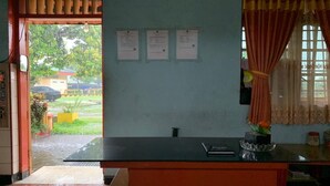 Una habitación con escritorio, ventana con cortinas y vista al exterior. Hay tres anuncios en la pared.
