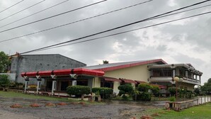 Un edificio de dos pisos con techo rojo y una fachada amplia y plana.