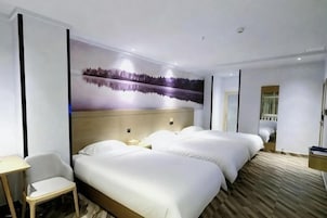 Quarto de hotel com duas camas, uma escrivaninha, uma cadeira e um grande mural na parede.