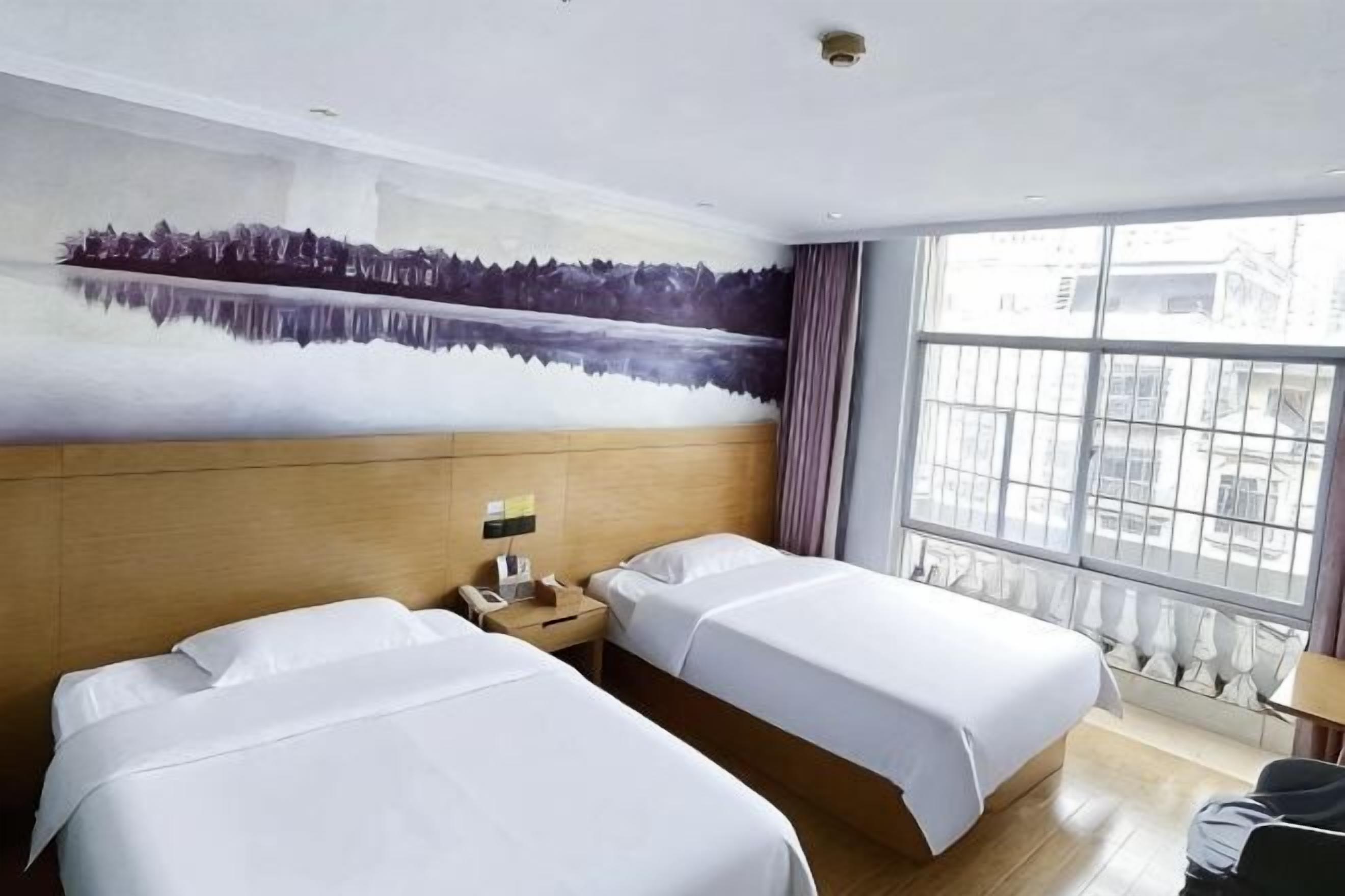 A hotel room with two beds, a large window, and a mural on the wall.