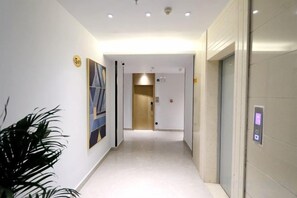 A hotel corridor with a modern design, including a hallway, elevator, and a potted plant. - Xilinger Hotel ( Dongxing Hezhou Road) (Dongxing)