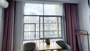 Ein Zimmer mit großem Fenster, einem Tisch mit Wasserkocher und einem Stuhl.