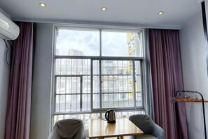 A room with a large window, a table with a kettle, and a chair. - Xilinger Hotel ( Dongxing Hezhou Road) (Dongxing)