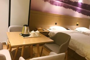 A hotel room with a bed, a chair, a table with a kettle and cups, and a nightstand with a phone. - Xilinger Hotel ( Dongxing Hezhou Road) (Dongxing)