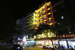 A multi-story hotel with illuminated signage and a visible balcony on the upper floors. - Xilinger Hotel ( Dongxing Hezhou Road) (Dongxing)