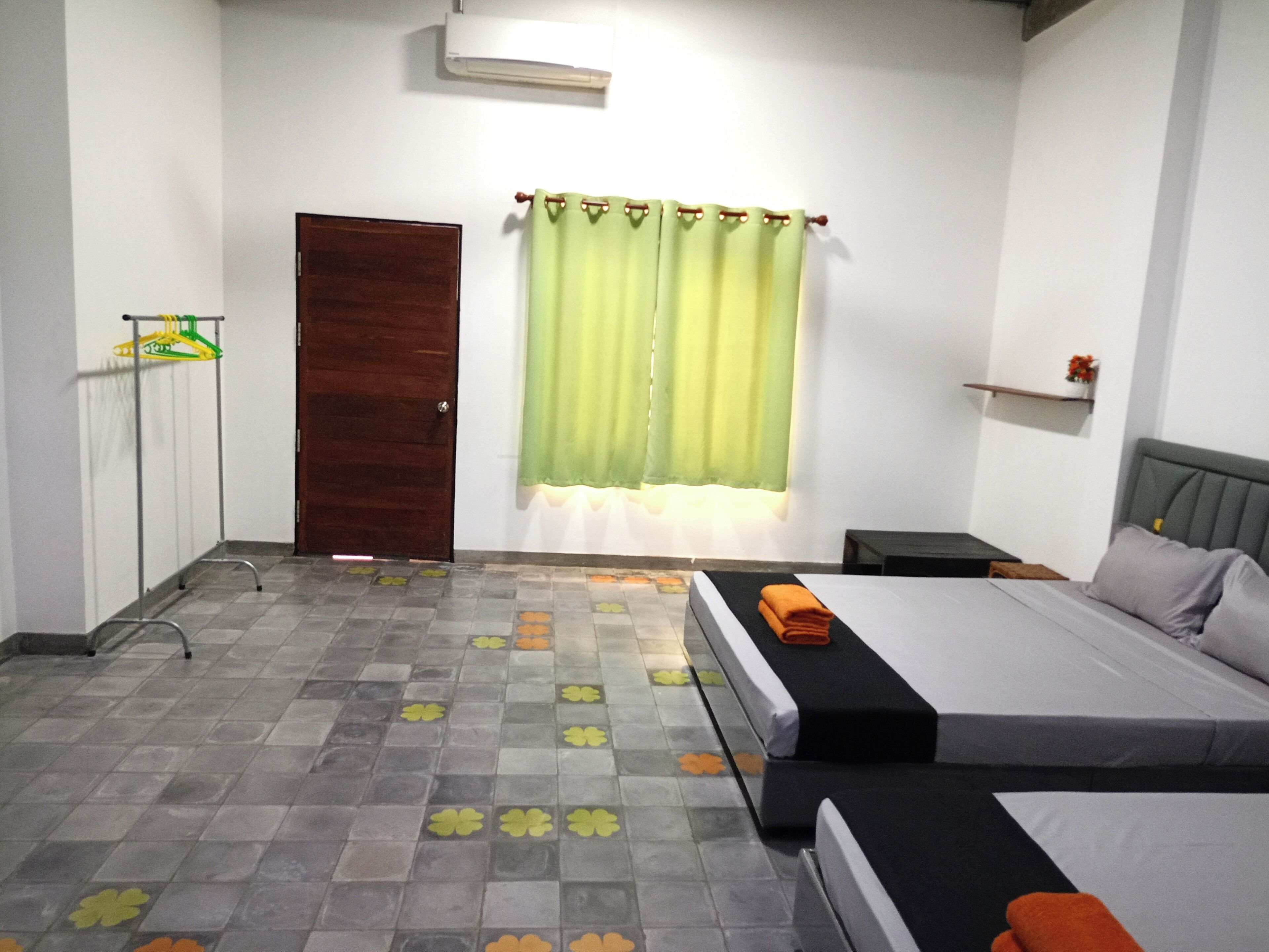 Ein Schlafzimmer mit einem Bett, einem Nachttisch, einer Holztür und einem Fenster mit grünen Vorhängen.