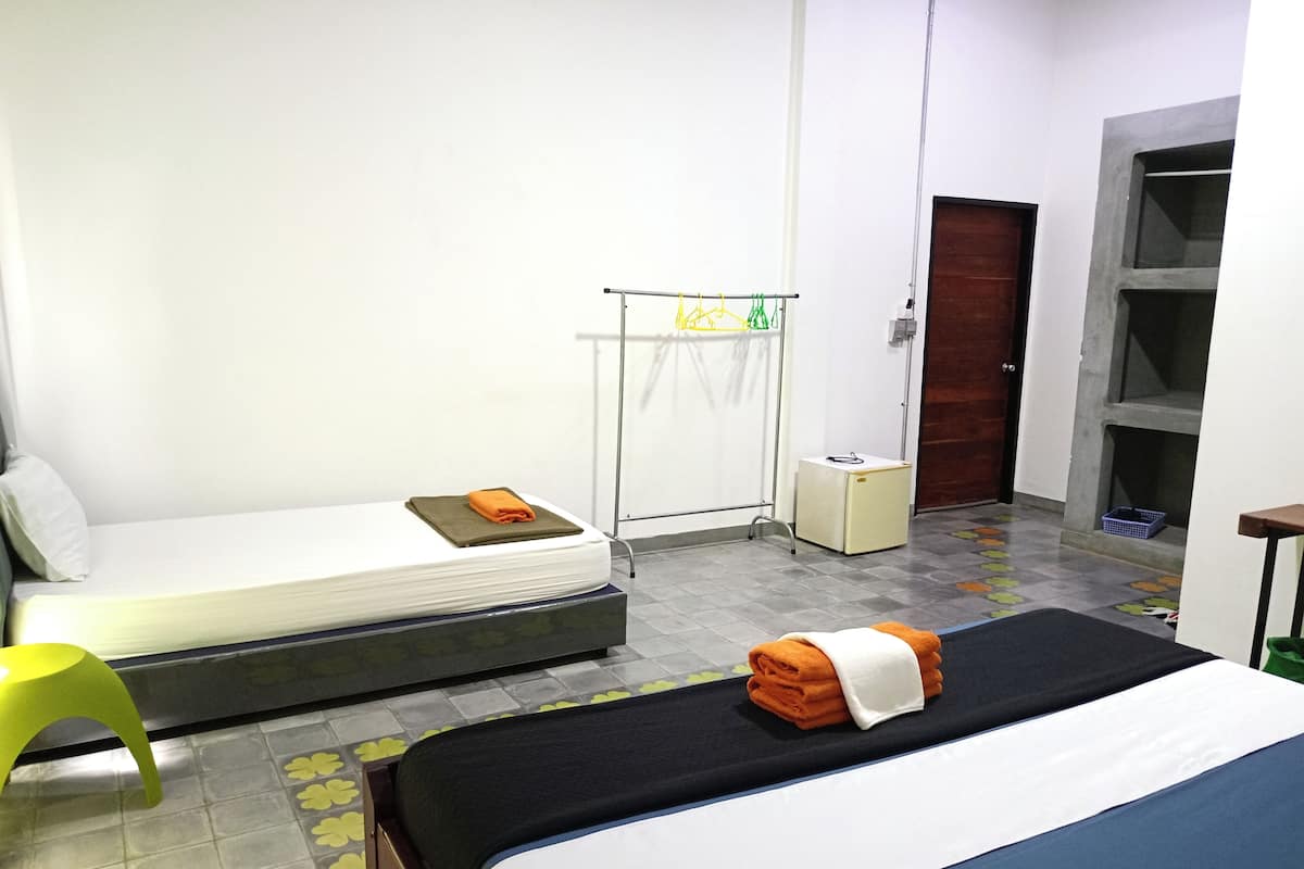 A hotel room with a bed, a small table, a chair, a wardrobe, and a door.