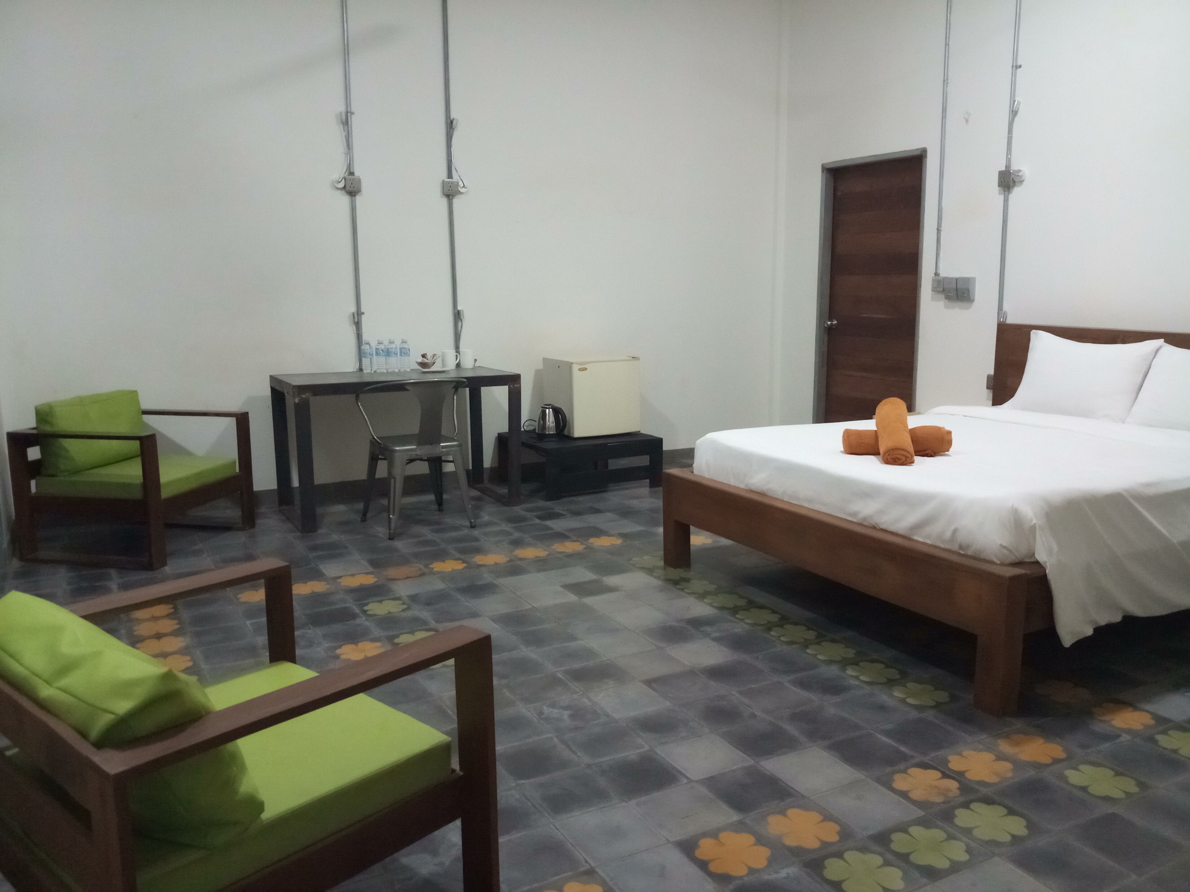 A hotel room with a bed, a desk, a chair, and a small table.