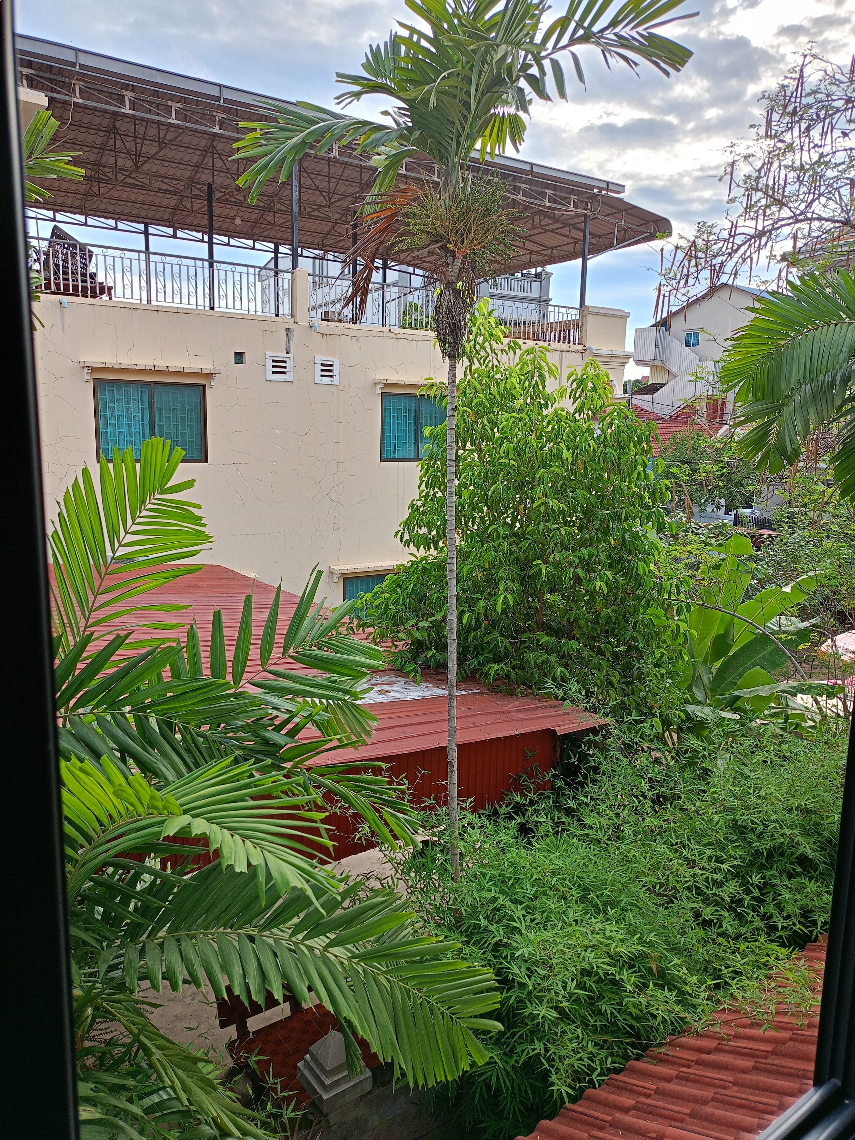A view of a residential area with houses, a red-roofed structure, and lush greenery.