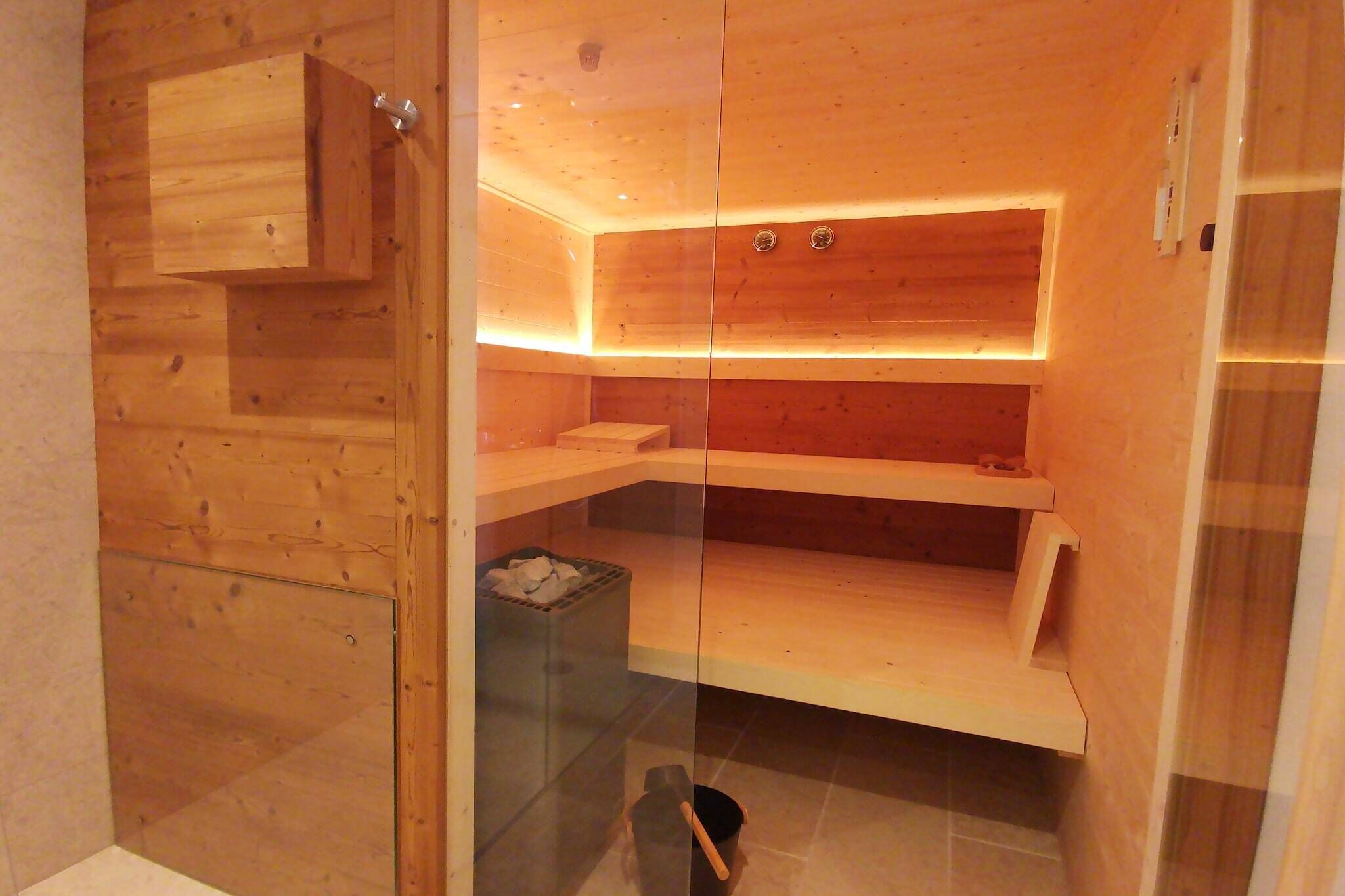 A modern wooden bathroom with built-in shelves and a glass partition.