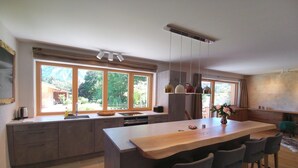 A modern kitchen with a large island, ample natural light from large windows, and a view of the outdoors.