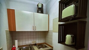 A compact kitchen with a sink, stove, and a coffee maker on the countertop. - Talgarten Studio 3 (Erfurt)