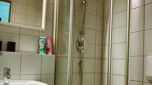 A bathroom with a glass-enclosed shower, a sink, and a mirror. - Talgarten Studio 3 (Erfurt)