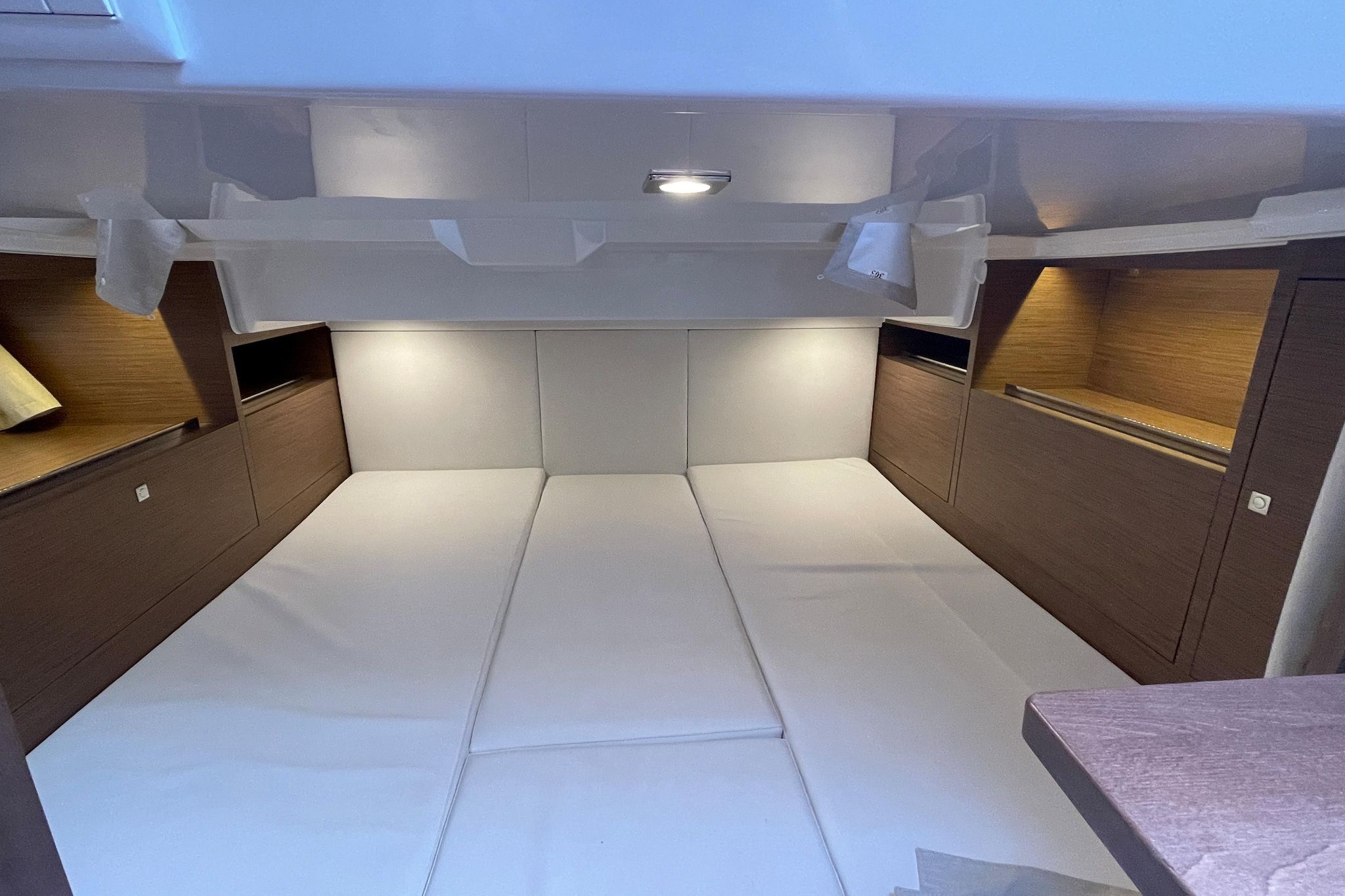 Un espace intérieur compact et bien éclairé, doté d’un coin salon central, de compartiments de rangement et d’un luminaire fixé au plafond.