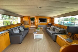 A modern interior with a sofa set, a coffee table, and a TV mounted on the wall. - Exclusive yacht with a roof terrace (La Rochelle)