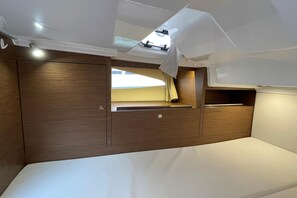 Ein gemütliches, helles Kabinett mit einem Einzelbett, Holzvertäfelung und einem kleinen Fenster.