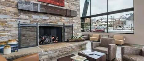 Una sala de estar moderna con chimenea de piedra, sofás de cuero y un gran ventanal con vistas al exterior.
