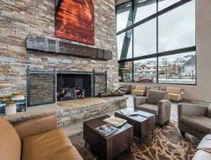 Un salon moderne avec une cheminée en pierre, des canapés en cuir et une grande fenêtre donnant sur l’extérieur.