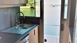 A compact kitchen with a sink, a window offering a view of a marina with boats and a dock. - Luxury yacht in La Rochelle with a terrace (La Rochelle)