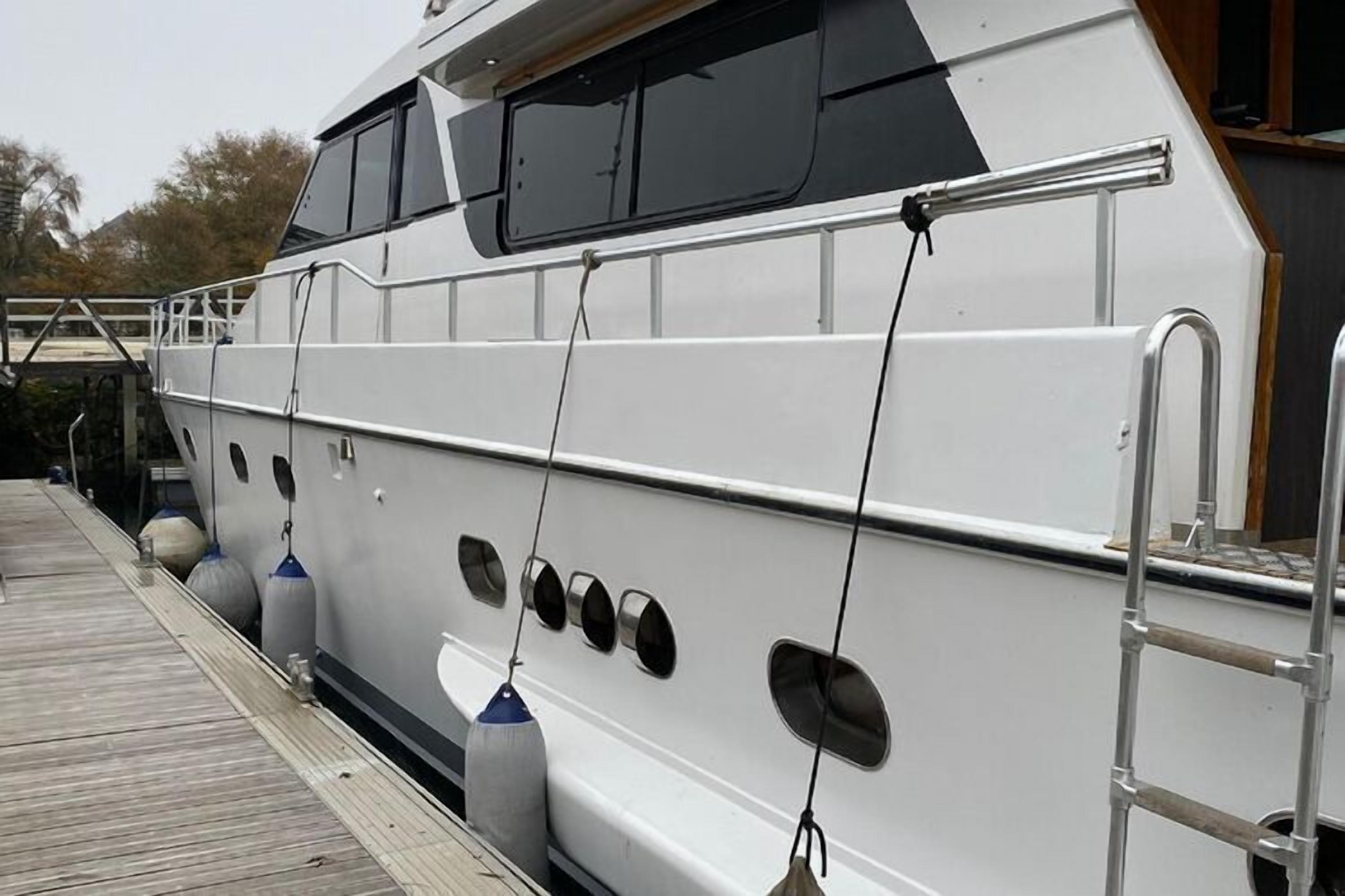Un yacht blanc était amarré à un quai, auquel était adossée une passerelle en bois.