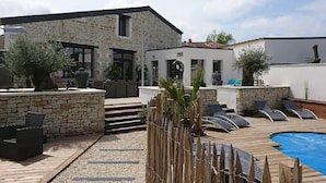 A stone building with a pool, outdoor seating, and a small structure with a clock.