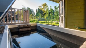 A hot tub with a view of a garden and a wooden deck.