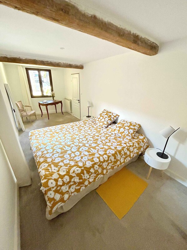Une chambre à coucher avec un lit, une table de chevet, une lampe et une fenêtre.