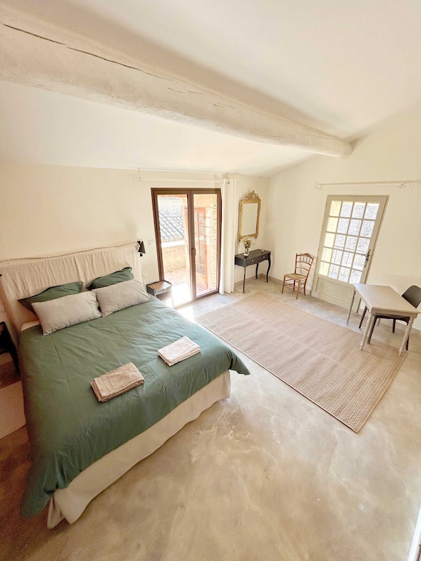 A bedroom with a bed, a desk, a chair, and a window.