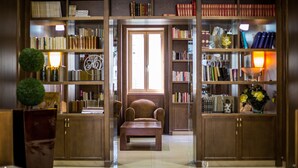 Una biblioteca con estanterías, un sillón de lectura y una mesa de madera.