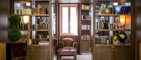 A library with bookshelves, a reading chair, and a wooden table.