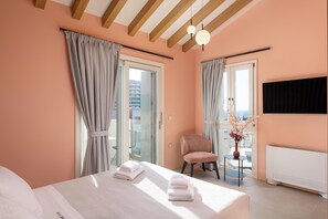 Une chambre d’hôtel avec un lit, une chaise, une petite table, un vase avec des fleurs et une vue par la fenêtre.