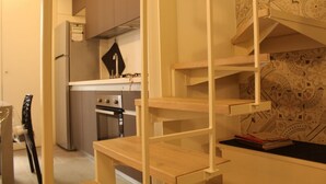 Une cuisine compacte équipée d’un four encastré, d’un réfrigérateur et d’une étagère en bois.