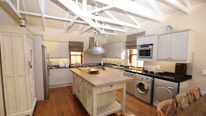A spacious kitchen with wooden flooring, a central island, built-in appliances, and a high ceiling with exposed beams. - LeBonheur (Cape Town)