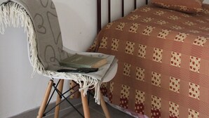 Une chambre à coucher comprenant un lit, une chaise et un panneau fixé au mur, sur lequel est inscrit un texte manuscrit.